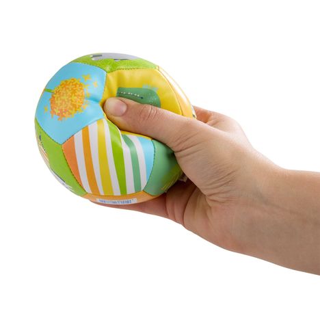 Ein Ball mit bunten Mustern, er wird von einer Hand gedrückt. Farben und Muster variieren auf den Ballflächen.