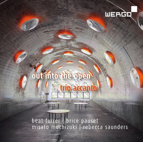 "out into the open" und "trio accanto" sind zentrale Texte. Grauer Tunnel mit runden Tischen und orange beleuchteten Öffnungen.