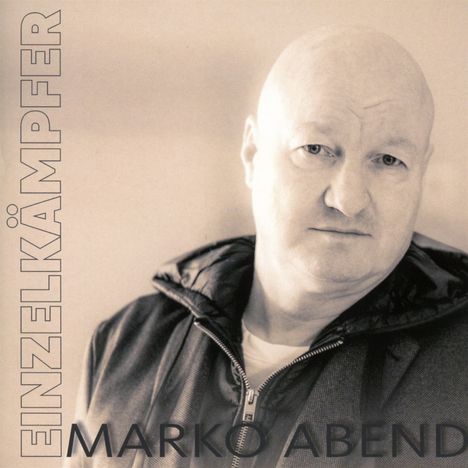 EINZELKÄMPFER, MARKO ABEND. Ein glatzköpfiger Mann in Jacke und Pullover vor unscharfem Hintergrund.