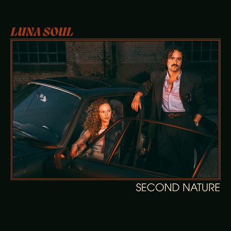 Oben steht "LUNA SOUL", unten "SECOND NATURE". Ein Mann lehnt an einem Auto, eine Frau sitzt darin.