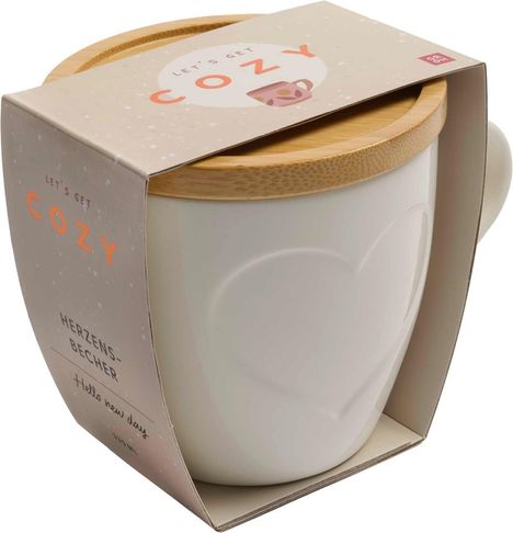 "Let's get cozy" und "Herzensbecher" zieren eine beige Verpackung mit Herzmotiv und Holzdeckel.