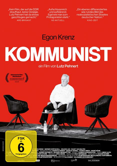 „Egon Krenz KOMMUNIST, ein Film von Lutz Pehnert. FSK ab 6 freigegeben.“ Zwei Sessel und ein Tisch auf rotem Hintergrund.