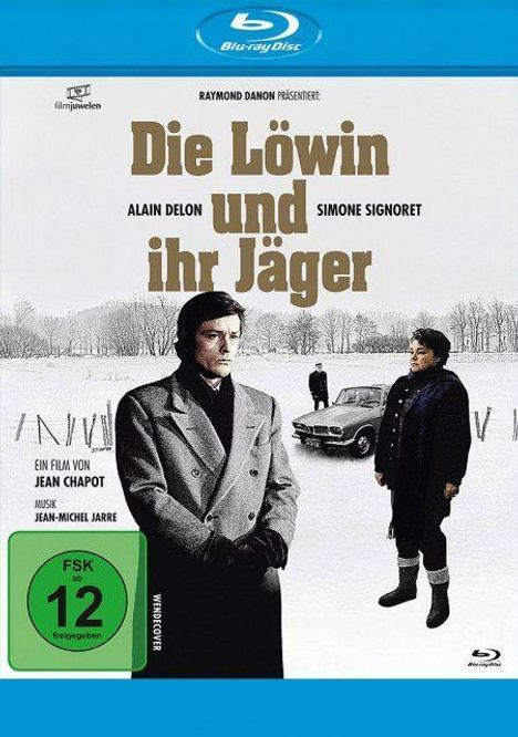 Titel: "Die Löwin und ihr Jäger". Darunter Alain Delon, Simone Signoret. Zwei Personen im Wintermantel vor einem Auto im Schnee.