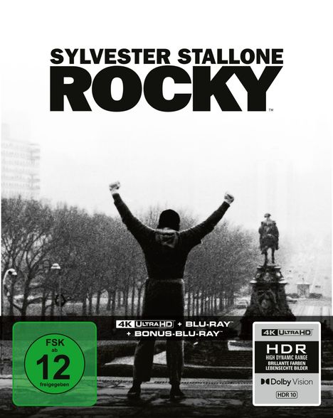 „SYLVESTER STALLONE ROCKY“ in großen Buchstaben. Darunter eine Person mit erhobenen Armen vor einer Allee.