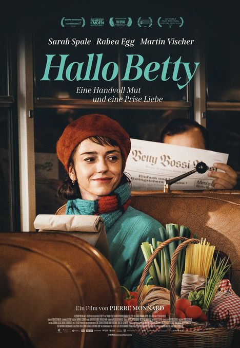 Titel: "Hallo Betty", Untertitel: "Eine Handvoll Mut und eine Prise Liebe". Frau in rotem Hut im Zug.