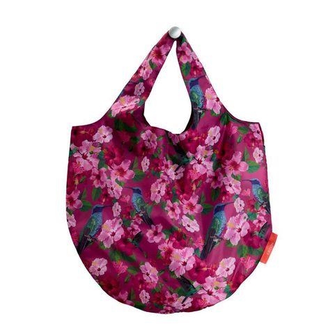 Das Wort "gusachi" steht auf einem Etikett. Die Tragetasche zeigt pinke Blumen und bunte Vögel auf violettem Hintergrund.