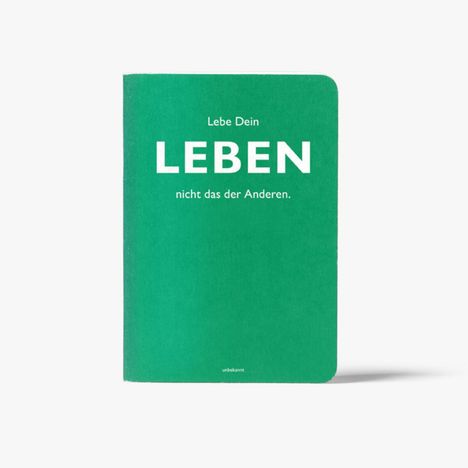 Grünes Notizbuch mit Aufschrift: "Lebe Dein LEBEN, nicht das der Anderen." Unten steht "unbekannt".