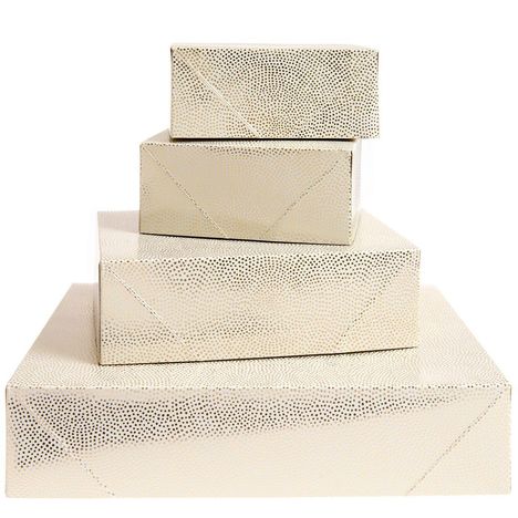 Keine Texte im Bild. Vier gestapelte, goldene Geschenkboxen mit gepunktetem Muster.