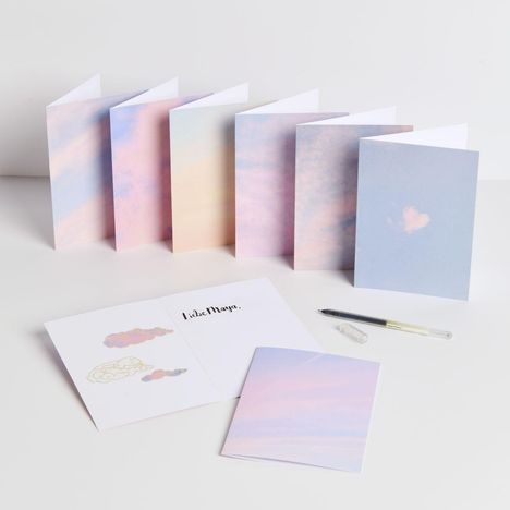 „Liebe Maya“ steht auf einer geöffneten Karte. Umschläge in sanften Pastellfarben, ein Kugelschreiber daneben.