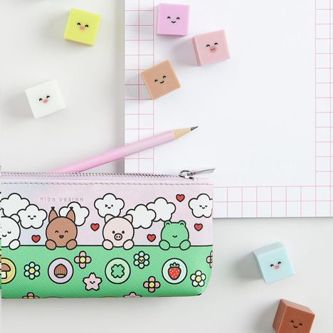 Pastellfarbene Radiergummis, lächelnde Gesichter, ein Federmäppchen mit Tier- und Wolkenillustration, rosa Bleistift.