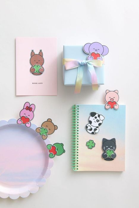 Karte mit "GOOD LUCK", Sticker: Tierfiguren halten Herzen und Kleeblätter, Geschenkbox mit Regenbogenschleife.