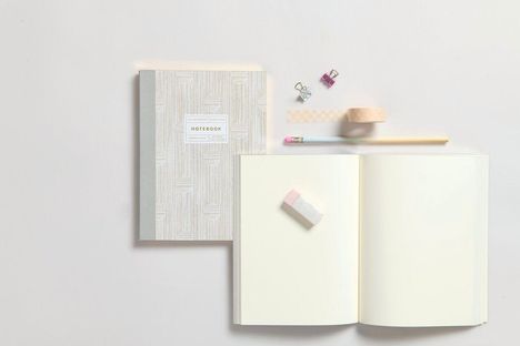 Notizbuch mit geometrischem Muster, offenes Notizbuch, Radiergummi, Stift, Washi-Tape und Klammern auf beigem Hintergrund.