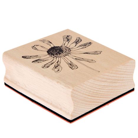 Ein hölzerner Stempel mit einer schwarzen, detaillierten Zeichnung einer Blume auf der Oberseite.