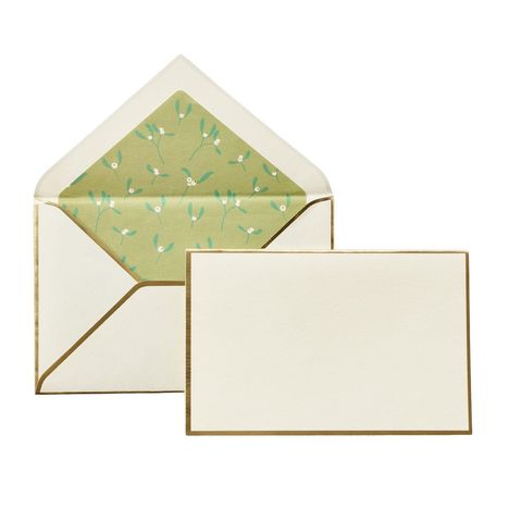 Ein leerer, cremefarbener Briefumschlag mit goldener Umrandung und passender Karte, Innenseite grün mit Blumenmuster.
