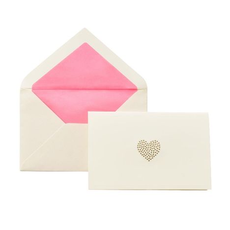 Eine Karte mit einem goldenen Herzsymbol, daneben ein offener Umschlag mit rosa Innenfutter.