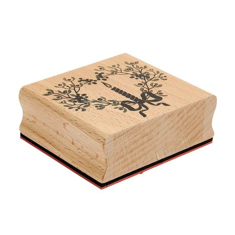 Ein Holzstempel mit schwarzem Muster: Einhorn mit Flügeln zwischen zwei dekorativen Ästen und Blättern.