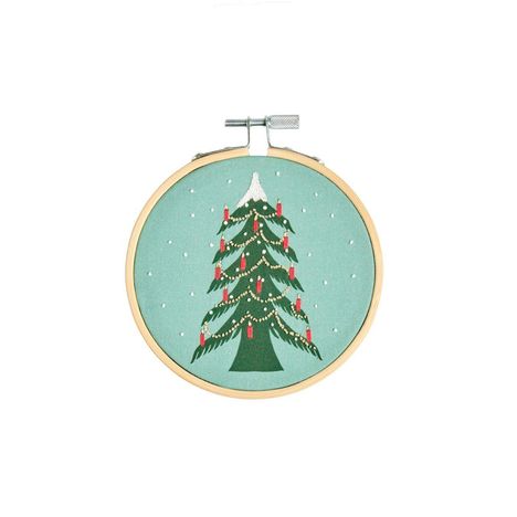 Illustration eines Weihnachtsbaumes in einem Stickrahmen, geschmückt mit roten Kerzen und Lichterkette auf grünem Hintergrund.