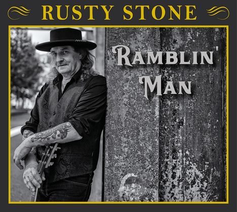 "RUSTY STONE", "RAMBLIN' MAN". Schwarz-Weiß-Foto eines Mannes mit Hut und Gitarre, an eine Wand gelehnt.
