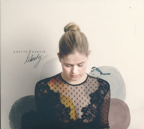 „ANETTE ASKVIK Liberty“ in schwarzer Schrift. Eine Frau mit hochgestecktem Haar und transparentem Spitzenoberteil.