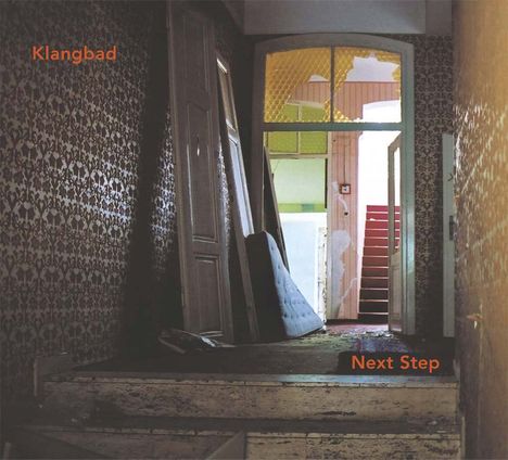 Texte: "Klangbad", "Next Step". Ein dunkler Flur führt zu einer helleren, zerbrochenen Türöffnung mit Sicht auf eine rote Treppe.