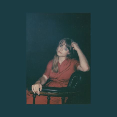 Eine Frau in rotem Kleid sitzt entspannt auf einem Stuhl und stützt ihren Kopf auf ihre Hand.