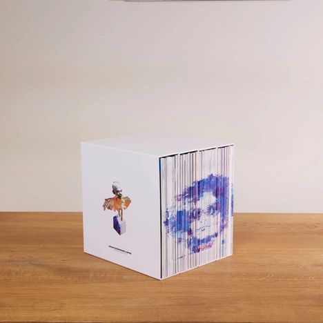 Box mit der Aufschrift "Omar Rodriguez-Lopez" und bunten Illustrationen, auf einem Holztisch.