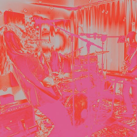 Roter und rosa Filter über einer Band mit Gitarren und Schlagzeug in einem Raum mit Vorhang.