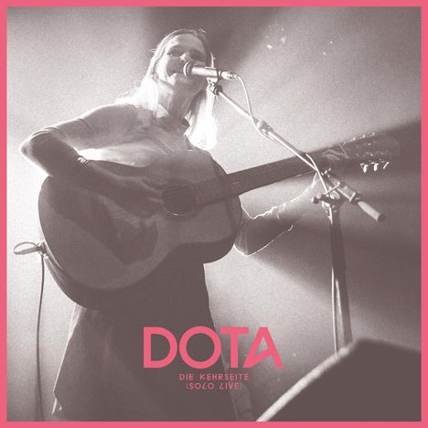 Text: "DOTA DIE KEHRSEITE (SOLO LIVE)"  
Frau mit Gitarre, singt in ein Mikrofon, Bühnenlicht.