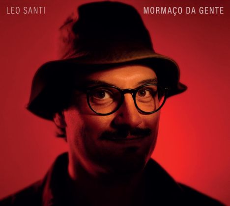 Oben links "LEO SANTI", rechts "MORMAÇO DA GENTE". Ein Mann mit Hut und Brille vor rotem Hintergrund.