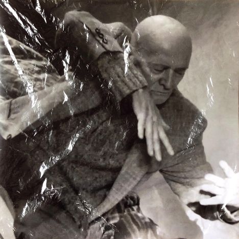 Ein Mann in einem Anzug steht mit verschränkten Armen. Er hat einen nachdenklichen Ausdruck und schaut leicht nach unten.