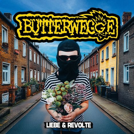 „Butterwegge“ und „Liebe & Revolte“. Kind mit Kapuze und Sonnenbrille hält Blumenstrauß in einer Wohnstraße.