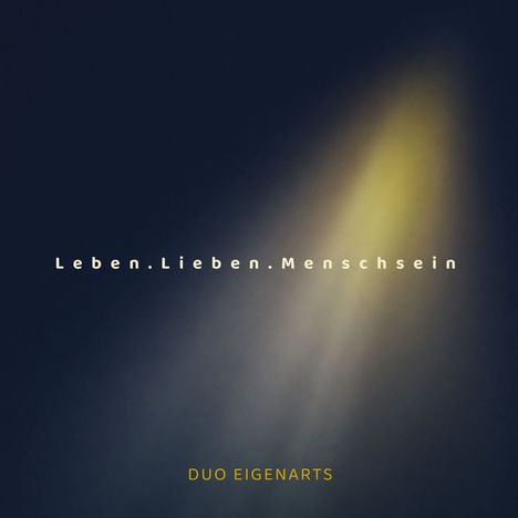 Text: "Leben.Lieben.Menschsein" und "DUO EIGENARTS". Dunkler Hintergrund mit einem gelben Lichtschein.