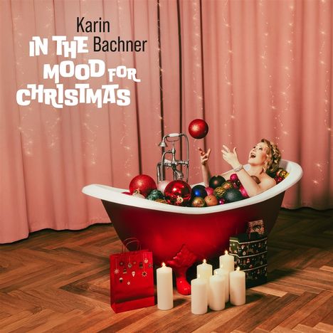 Text: "Karin Bachner IN THE MOOD FOR CHRISTMAS". Eine Frau in einer roten Badewanne voller Weihnachtskugeln.