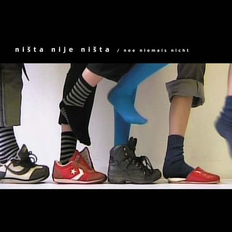Text: "ništa nije ništa / nee niemals nicht". Vier Füße mit bunten Socken und Schuhen in einer Reihe.