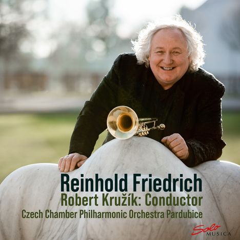 Reinhold Friedrich, Robert Kruží: Conductor, Czech Chamber Philharmonic Orchestra Pardubice. Mann mit Trompete lächelt.
