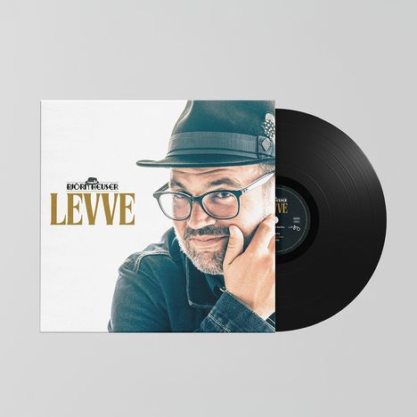 Text: "BJÖRN HEUSER LEVVE." Vinyl-Plattencover zeigt einen Mann mit Brille und Hut, nachdenklich posierend.