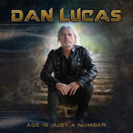 Oben steht "DAN LUCAS", unten "AGE IS JUST A NUMBER". Ein Mann in schwarzer Lederjacke sitzt auf Bahnschienen.