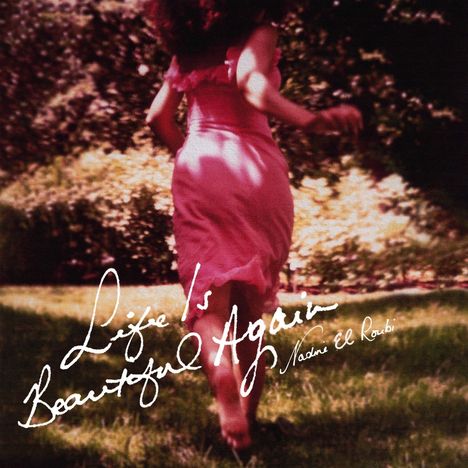„Life is Beautiful Again“ Nadine El Roubi. Frau in rosa Kleid läuft durch sonnigen Garten.