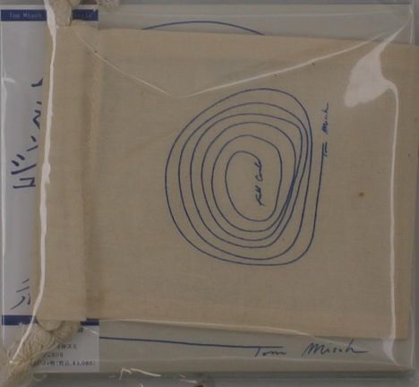 Eine beige Stofftasche zeigt blaue konzentrische Linien mit "Feel Cool" in der Mitte. Darunter steht "Tom Misch".