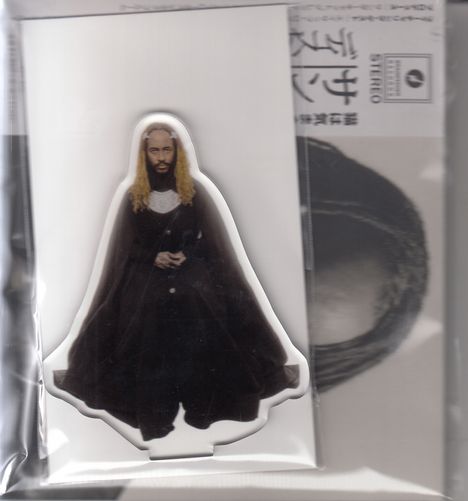 Text: "STEREO". Illustration eines Mannes mit langem, blondem Haar und dunklem Gewand auf grauem Hintergrund.