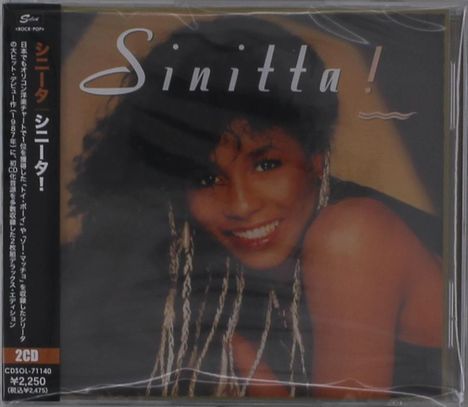 "Sinitta!" steht im Zentrum. Links vertikal japanischer Text. Eine lächelnde Frau mit lockigem Haar ist abgebildet.