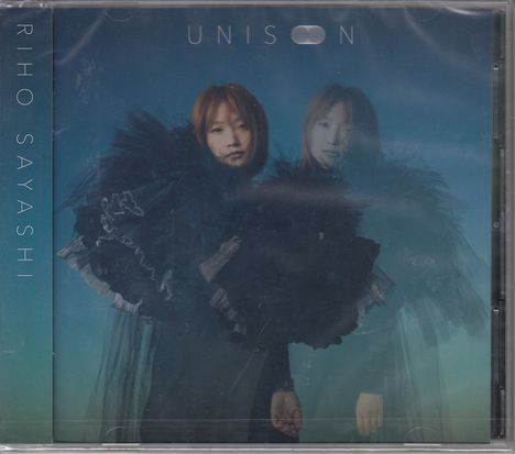 "UNISON" und "RIHO SAYASHI" mit einer Frau in voluminöser, schwarzer Kleidung vor blauem Hintergrund.