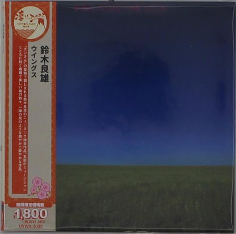 Japanische Schriftzeichen links auf orangem Band, darunter „1,800“. Dunkler Himmel über grünem Feld.