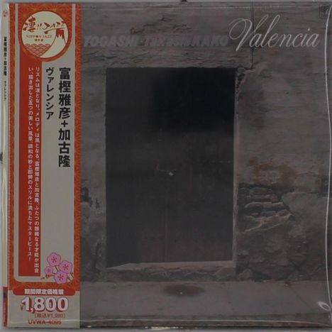 Valencia. Vertikal japanischer Text auf rotem Band links. Steinwand mit bröckelnder Oberfläche im Hintergrund.