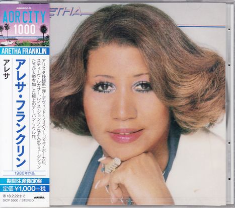 "Aretha Franklin" und japanische Schriftzeichen. Frau mit glatt gestyltem Haar lächelt sanft, ihr Kopf ruht auf einer Hand.