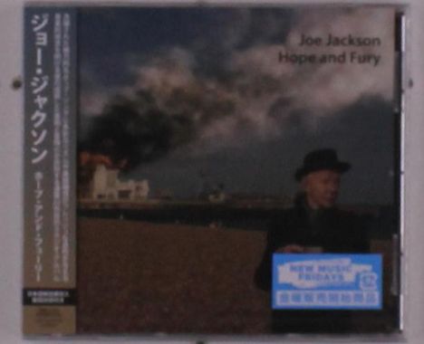 Text: "Joe Jackson Hope and Fury". Japanischer Text auf der Seite. Ein Mann in schwarzem Mantel und Hut vor rauchenden Gebäuden.