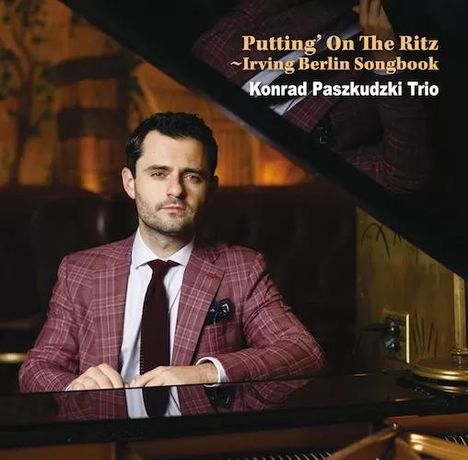 Text: "Putting' On The Ritz ~ Irving Berlin Songbook, Konrad Paszkudzki Trio." Ein Mann in einem karierten Anzug am Klavier.