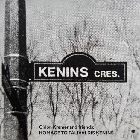 Straßenschild mit "KENINS CRES." und Text: "Gidon Kremer and friends: HOMAGE TO TĀLIVALDIS ĶENIŅŠ". Im Hintergrund Bäume.