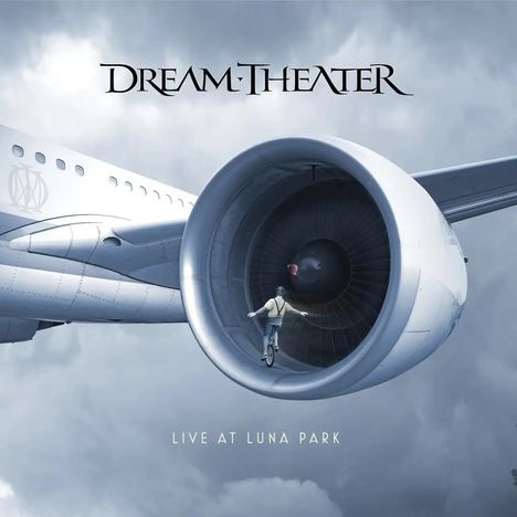 "Dream Theater", "Live at Luna Park". Ein Mann fährt auf einem Einrad im Triebwerk eines großen Flugzeugs in den Wolken.