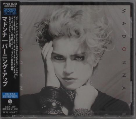 Schwarz-weißes Cover mit "MADONNA" vertikal am Rand. Frau mit lockigem Haar und Armbändern. Japanischer Text links.